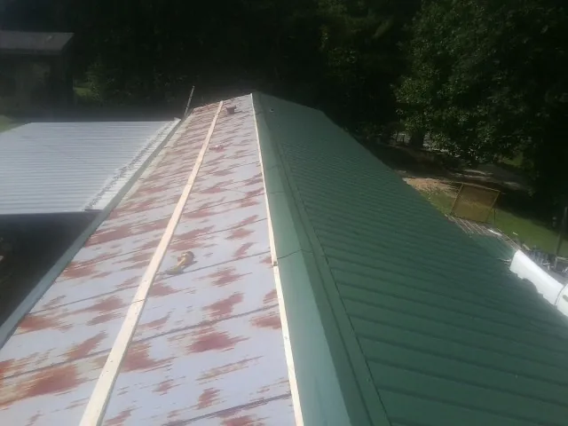 Old rusted panels beside newly installed green metal roofing — Wind Damage Roof Repair by Roofing Brothers in Kenansville